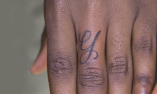Eine Hand mit einem tattowierten Buchstaben auf dem Zeigefinger