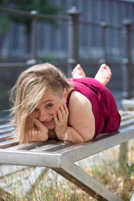 Porträtfoto von Jana Zöll, sie liegt auf einer Bank und lächelt in die Kamera